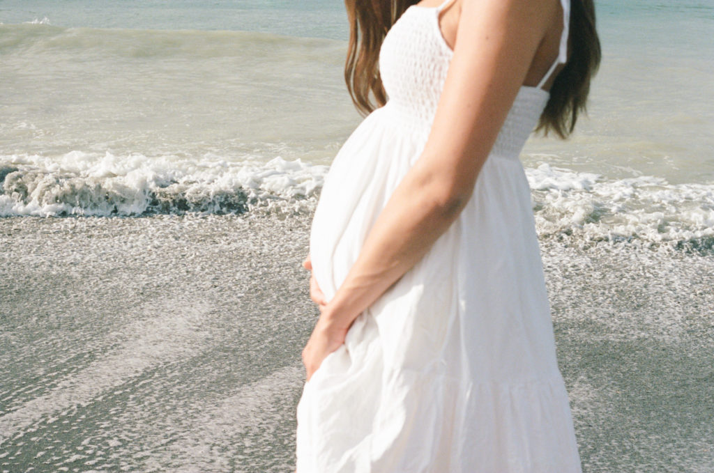 Close up maternity photo on film at the beach with mom in white dress by Maternity Photographer in Charleston, SC