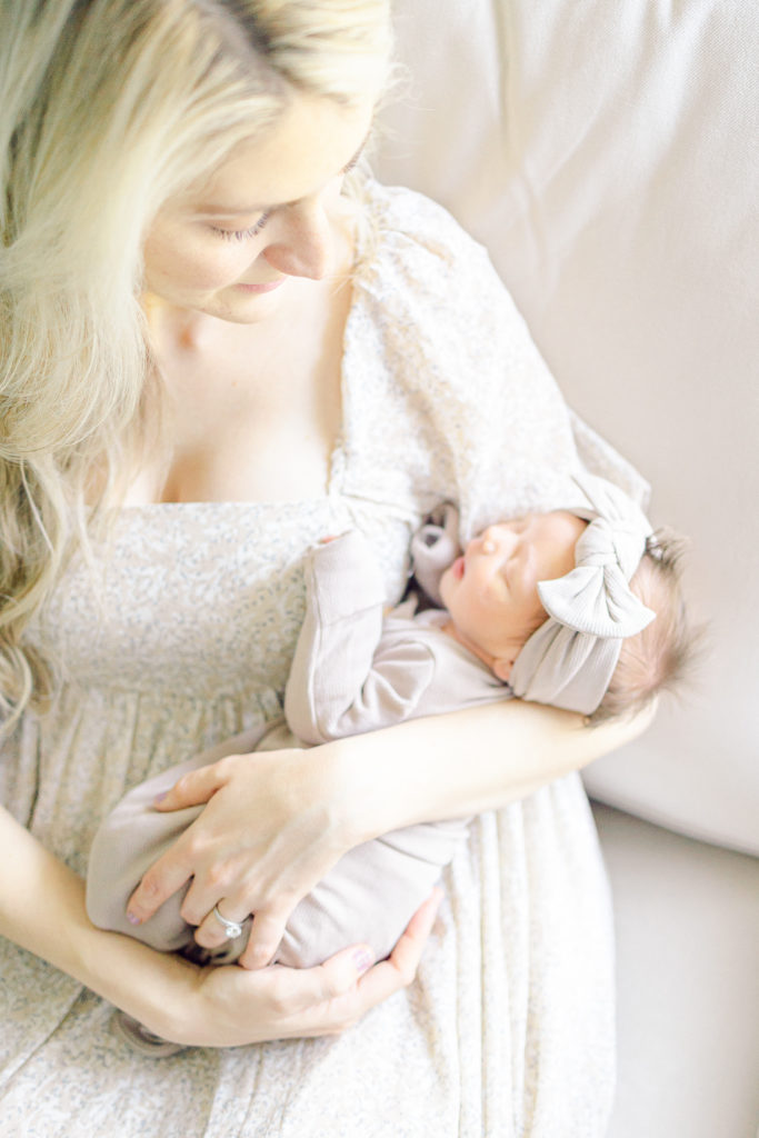 Mom in a Floral Dress, With Baby in a Brown Outfit, in the Nursery, Taken by Lifestyle Photographer in Charleston, SC