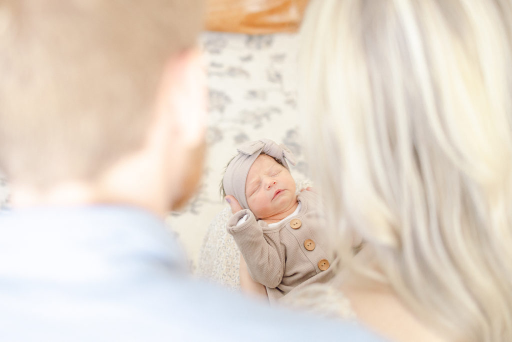 Looking at Baby Girls Face Through The Gap Between Mom and Dads Shoulders, Taken by Lifestyle Photographer in Charleston, SC