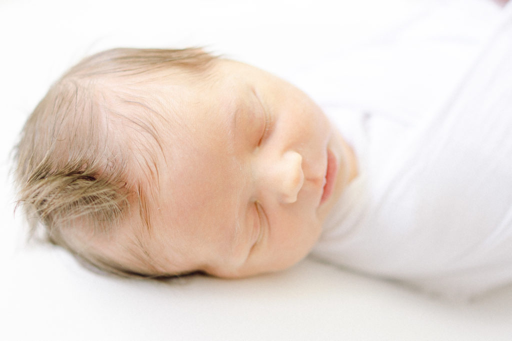 Detailed Newborn Portrait of Baby Girls Face on a White Backdrop, Taken by Lifestyle Photographer in Charleston, SC