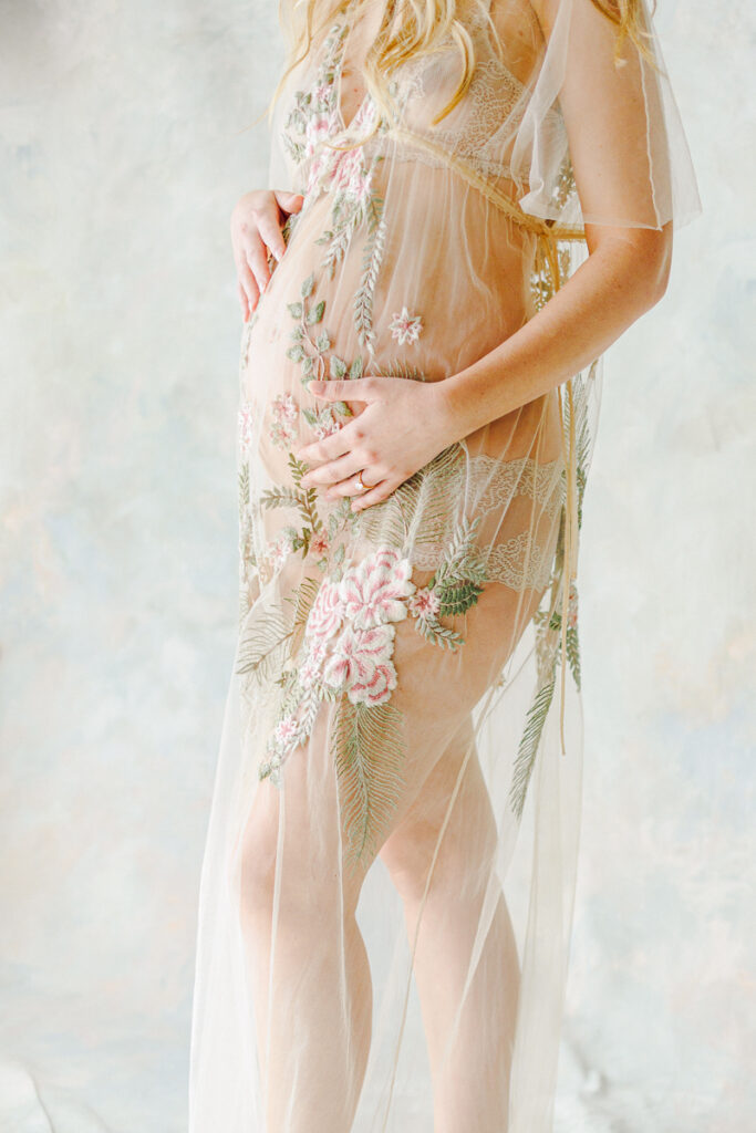 Pregnant mom holding her stomach in a sheer floral dress