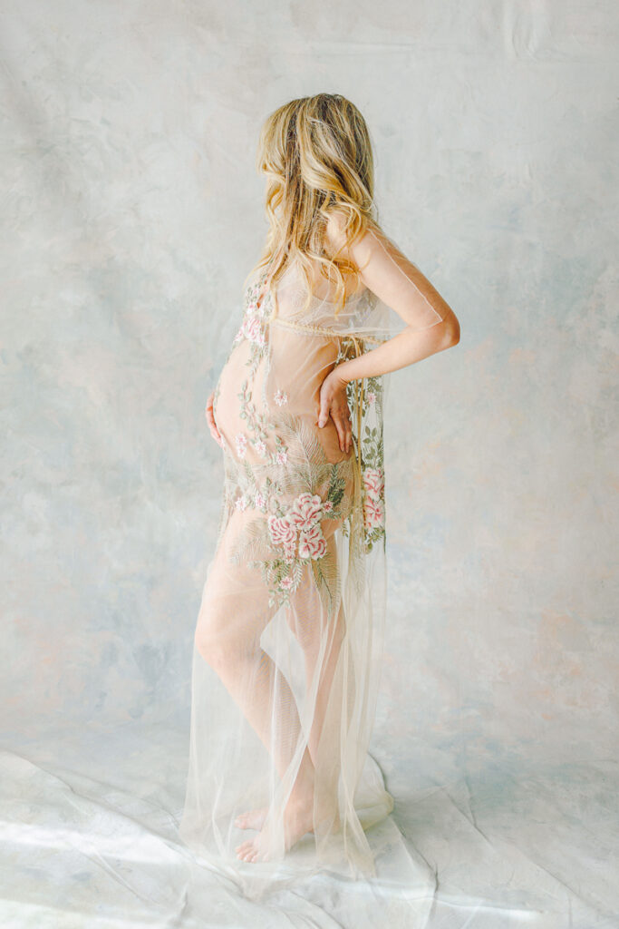 Studio maternity photo with mom a tulle dress facing away from the camera